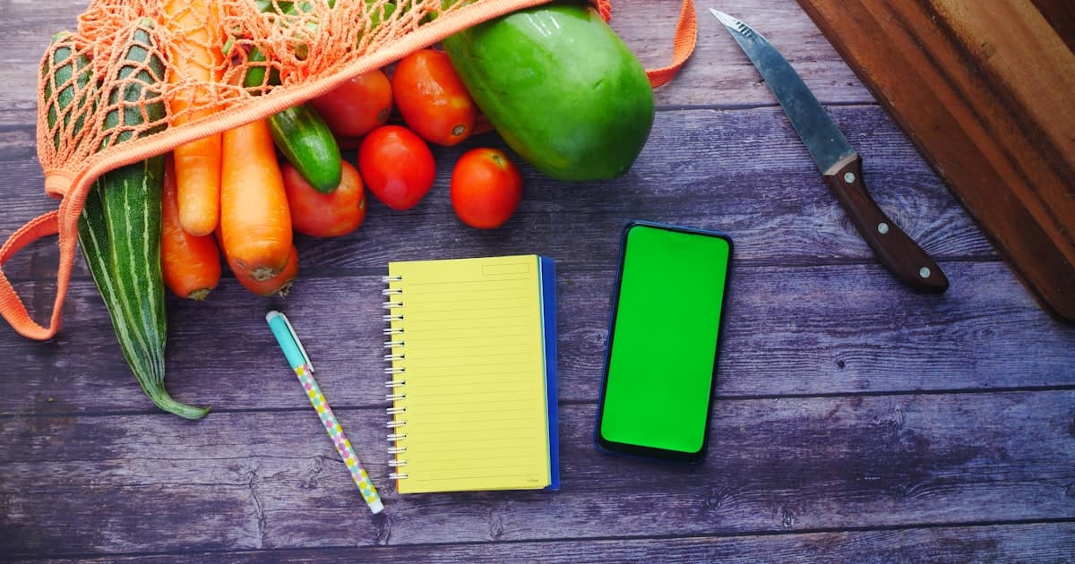 A notebook for meal planning alongside fresh vegetables